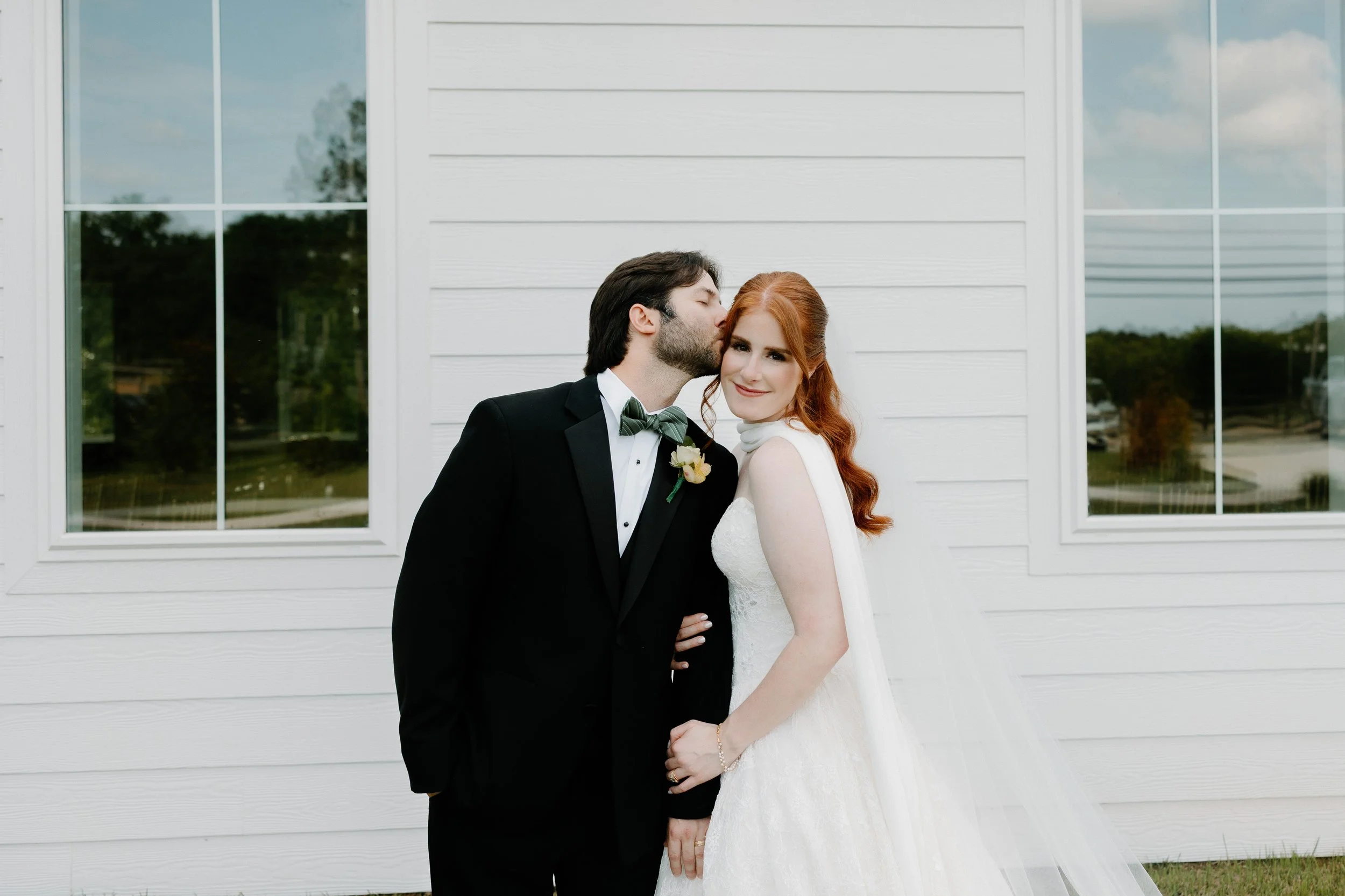 Bride and groom take outdoor portraits by the chapel at Kingfisher Lodge venue.