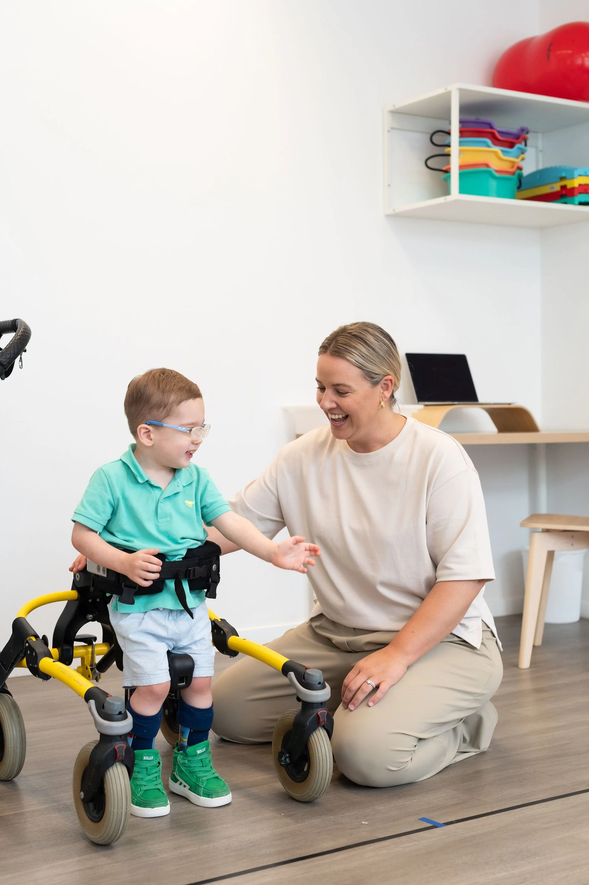 Therapist helping young boy with coordination using balance bike indoors