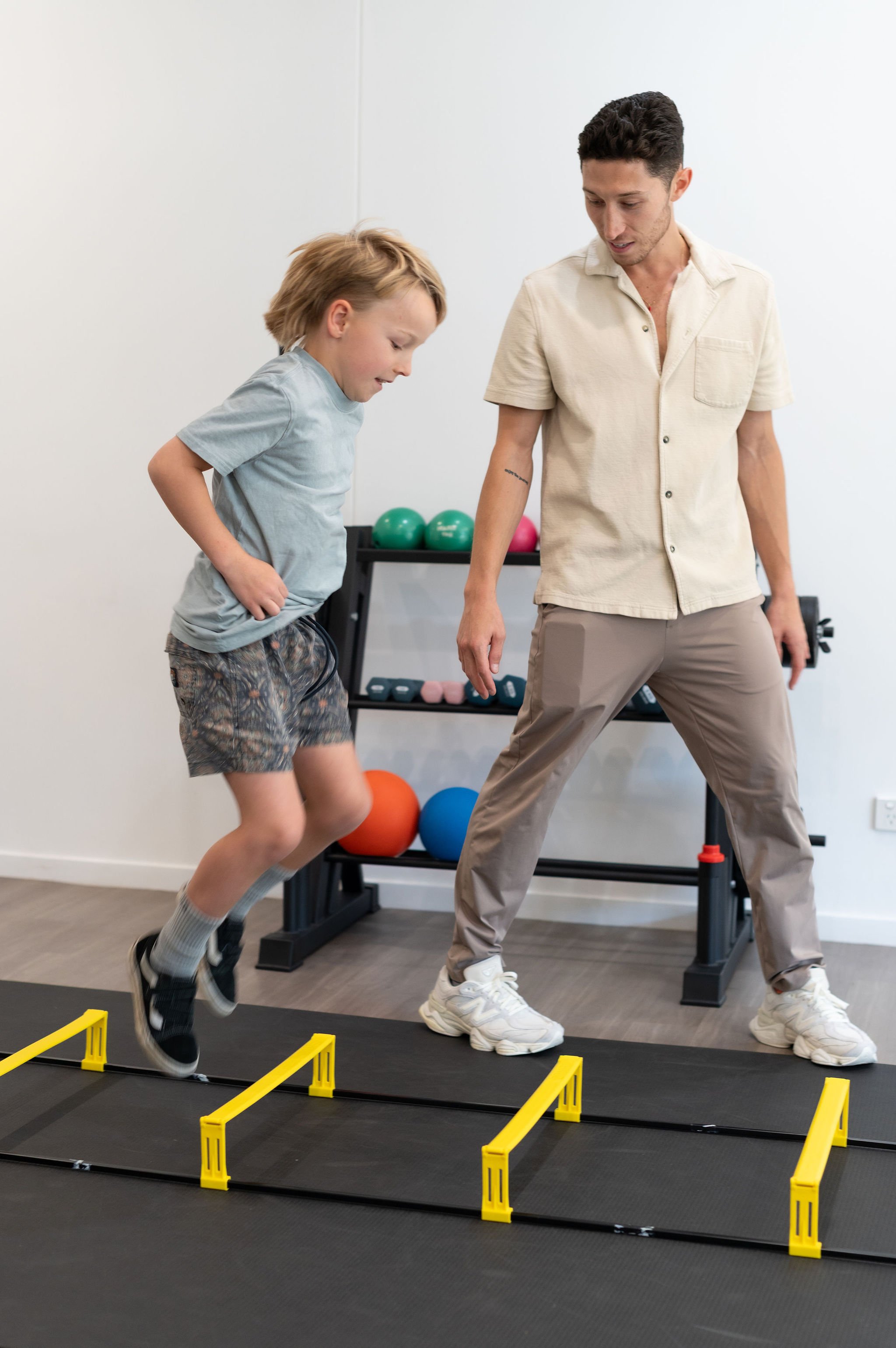 Child stepping through agility ladder under therapist guidance to improve coordination