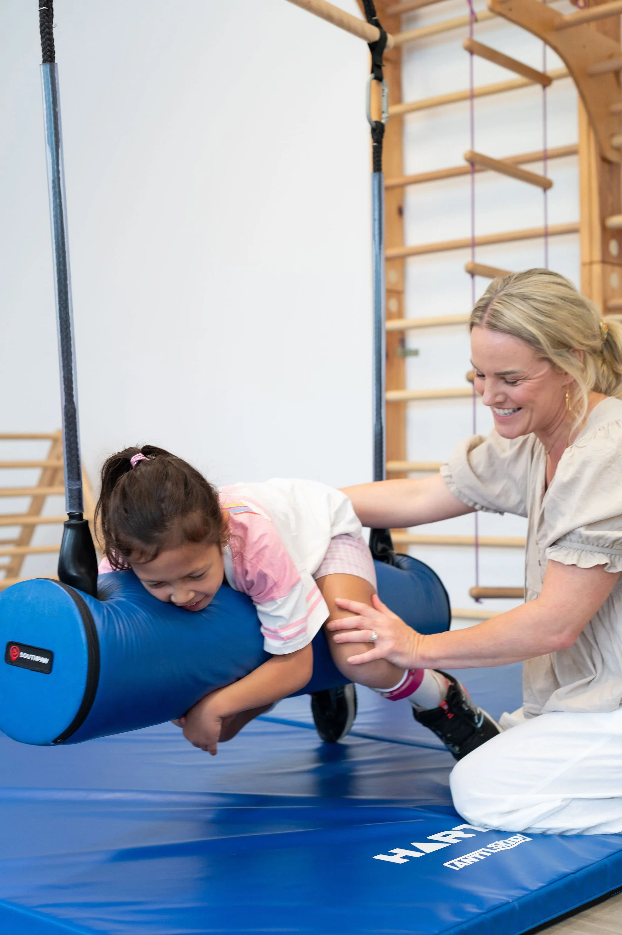 Child receiving support while using a sensory swing during paediatric physiotherapy session