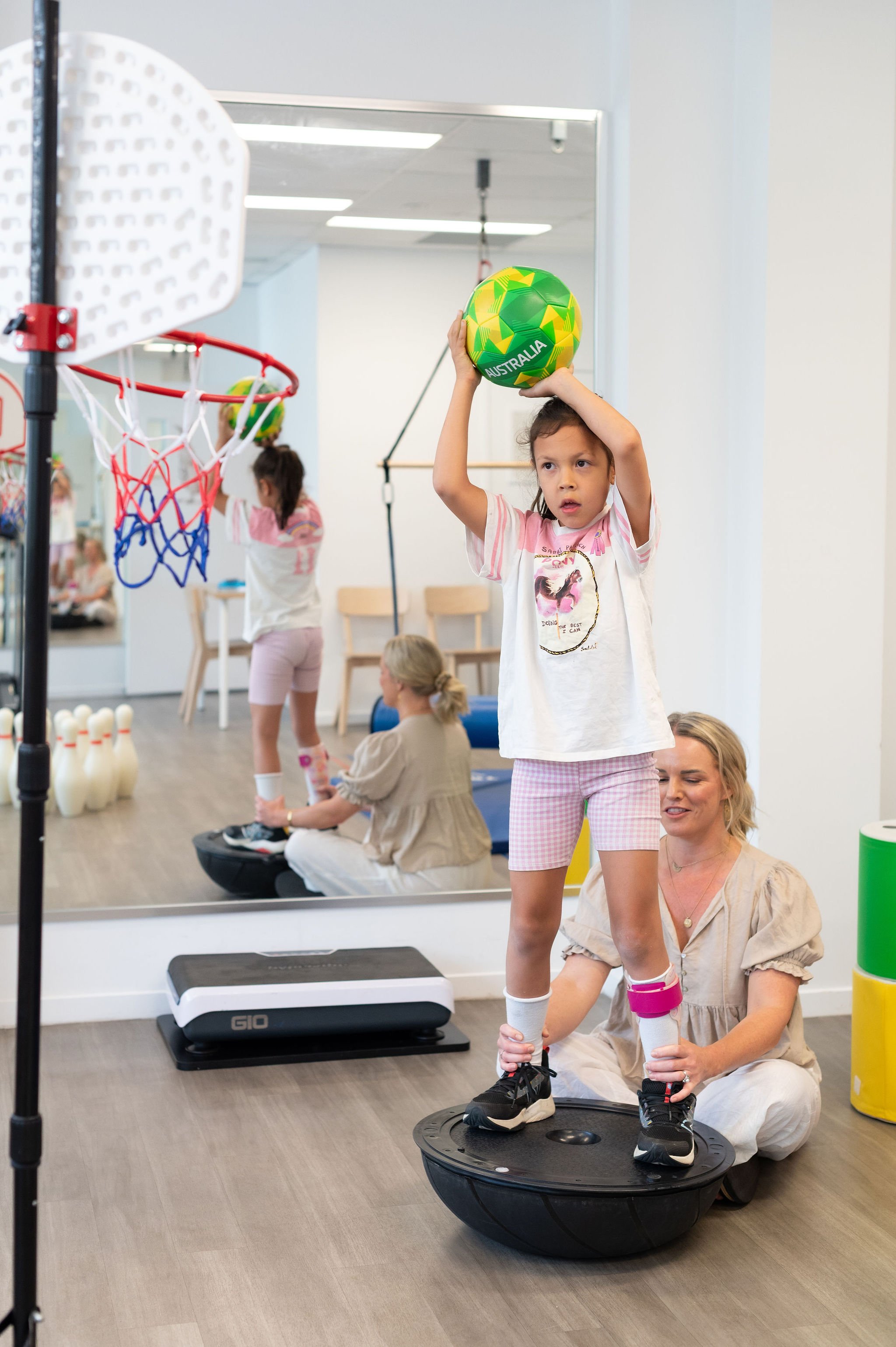 Young girl throwing basketball with therapist during engaging therapy session