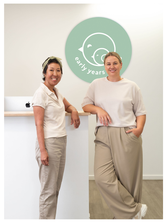 Early Years Physio team members standing at reception in front of clinic logo