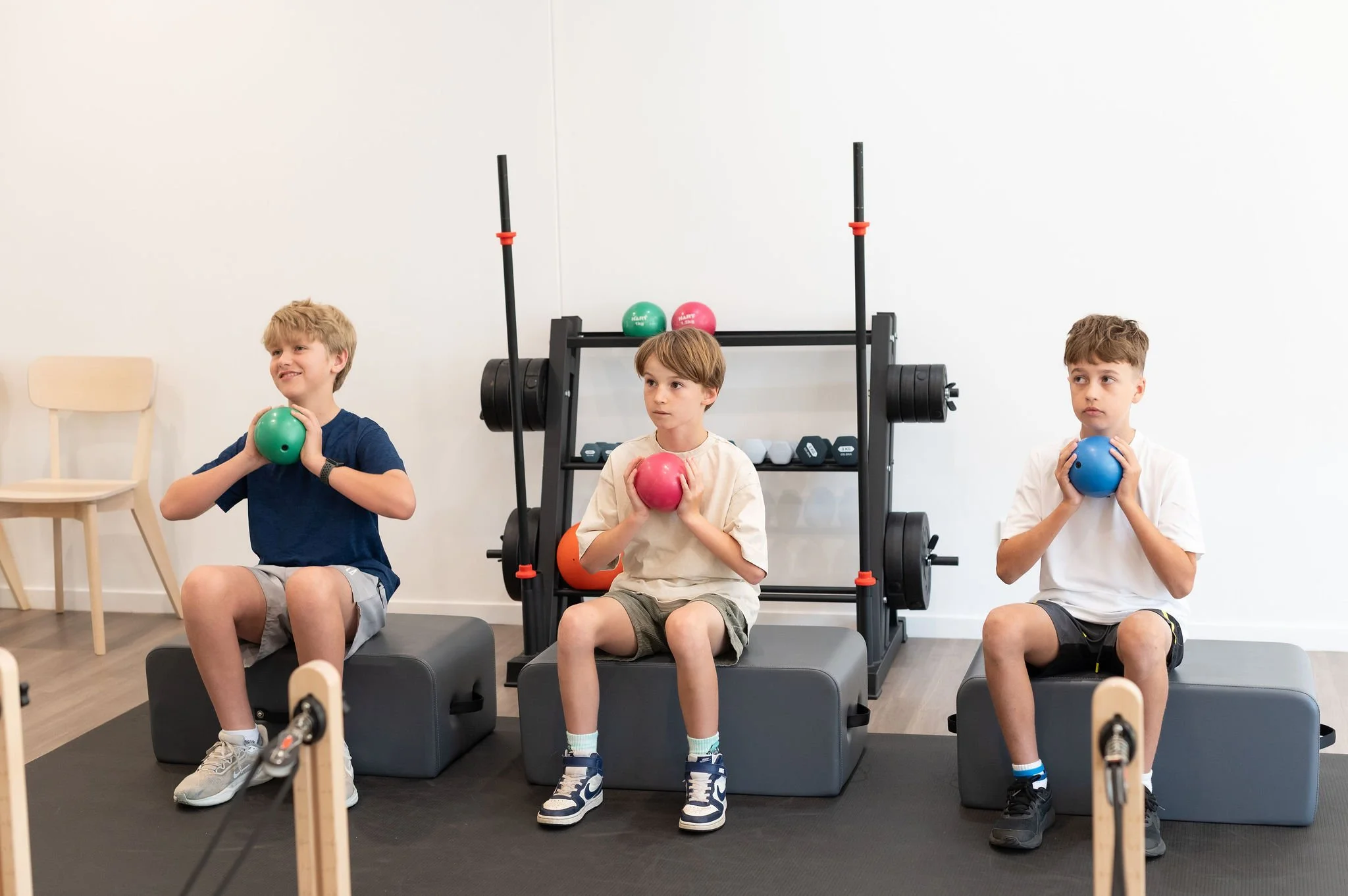 Children engaging in strength training exercises with dumbbells during physiotherapy session