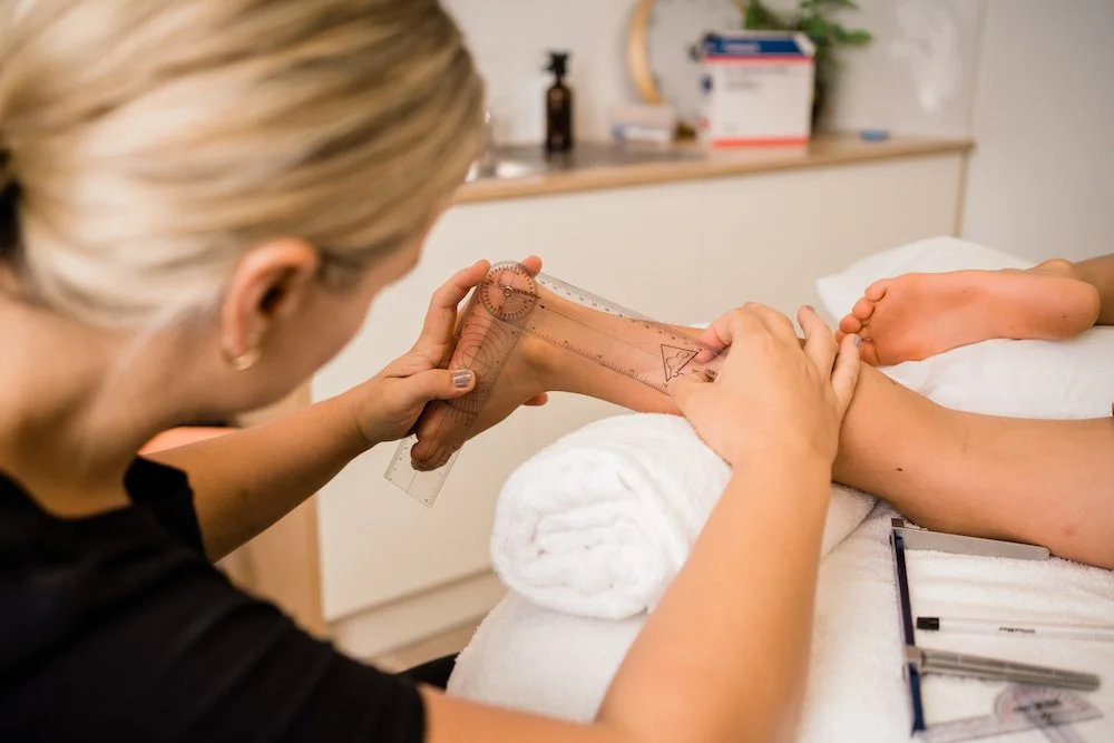 Physiotherapist applying a soft cast to child’s lower leg during serial casting procedure