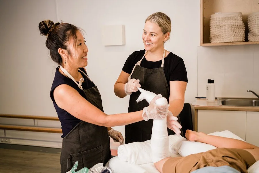 Two physiotherapists working together to apply a cast on a child’s arm during therapy