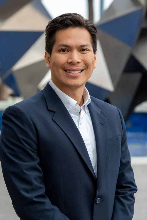 Team headshot of a man in a navy suit outdoors in the Bay Area