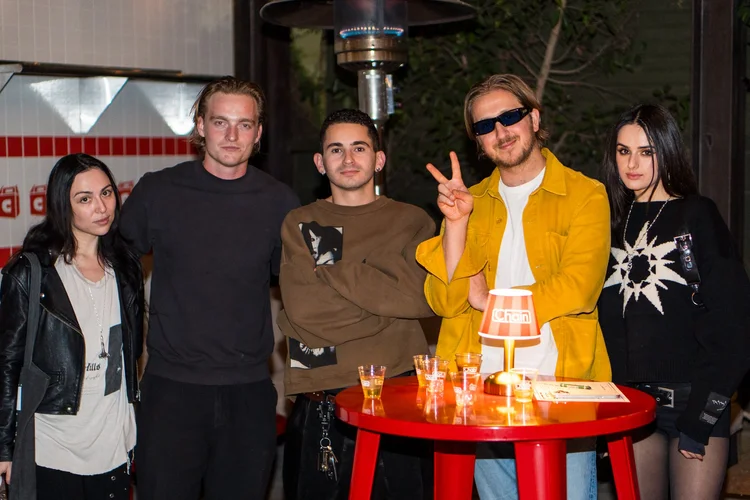 Guests posing at a red table at a Chain brand event
