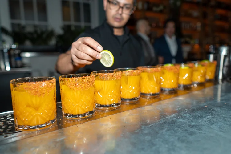 Bartender garnishing a row of cocktails at the Sesame AI holiday party