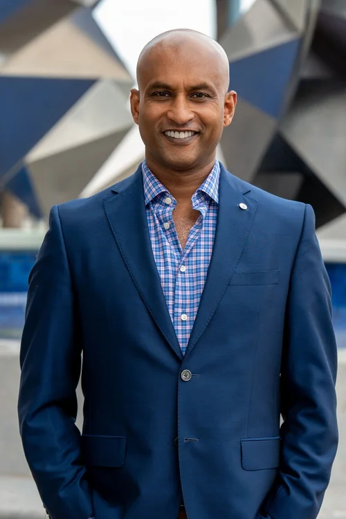 Team headshot of a man in a navy blazer outdoors in the Bay Area