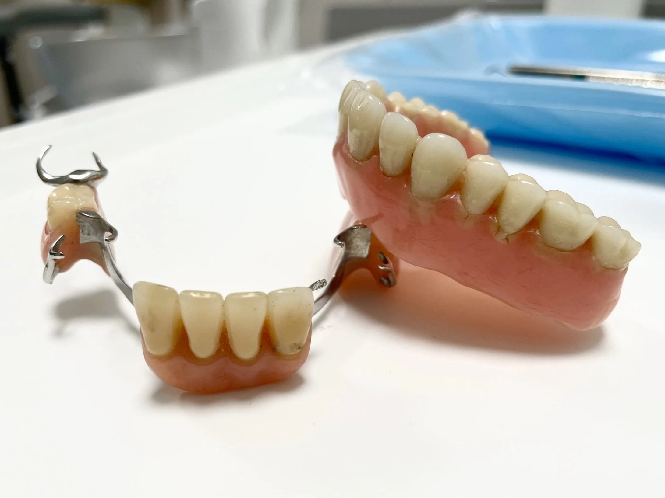 Dental prosthetic teeth and a metal framework for dentures placed on a white surface.
