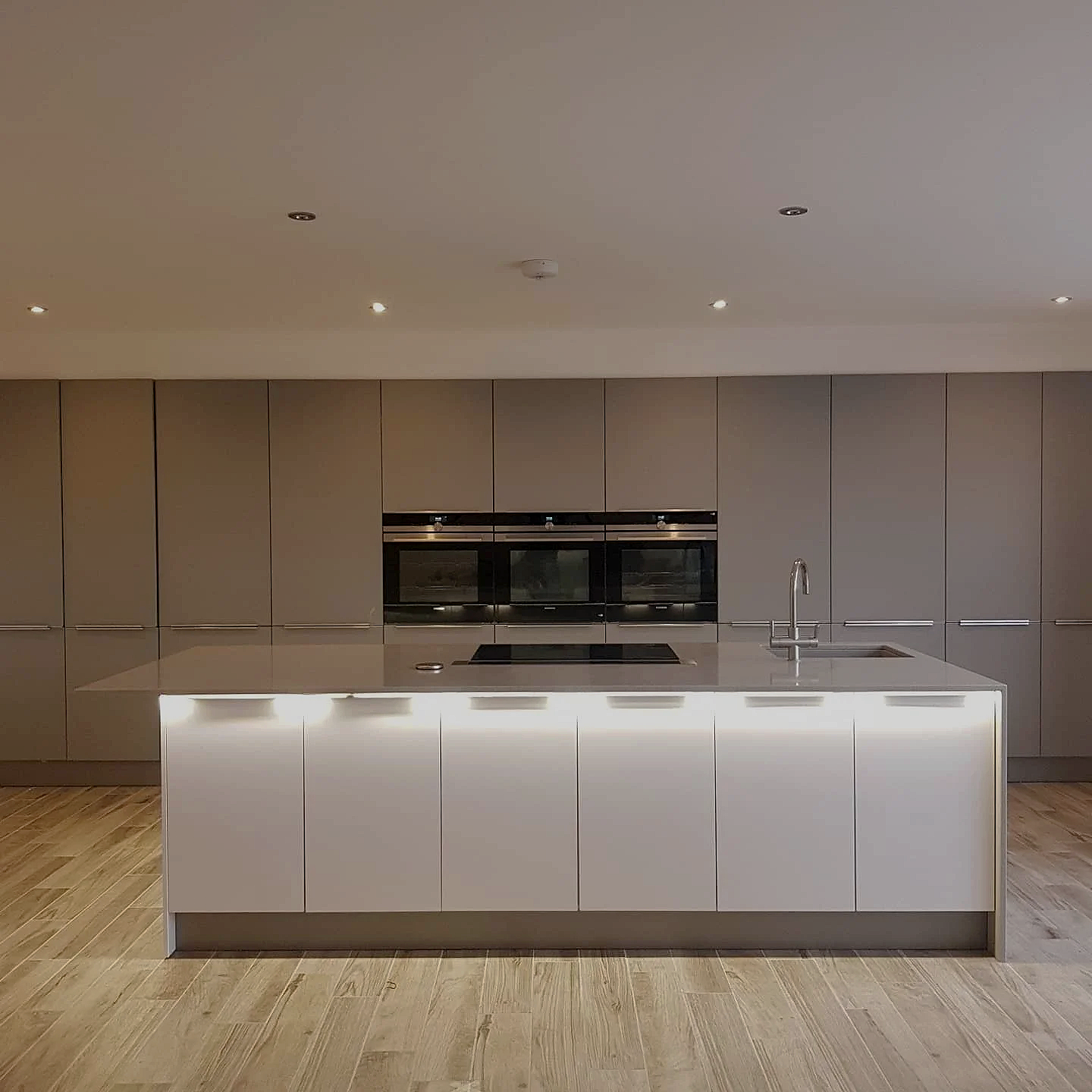 A Wall of Minimalist  kitchen with a wall of Tower Units and a huge elongated Island  