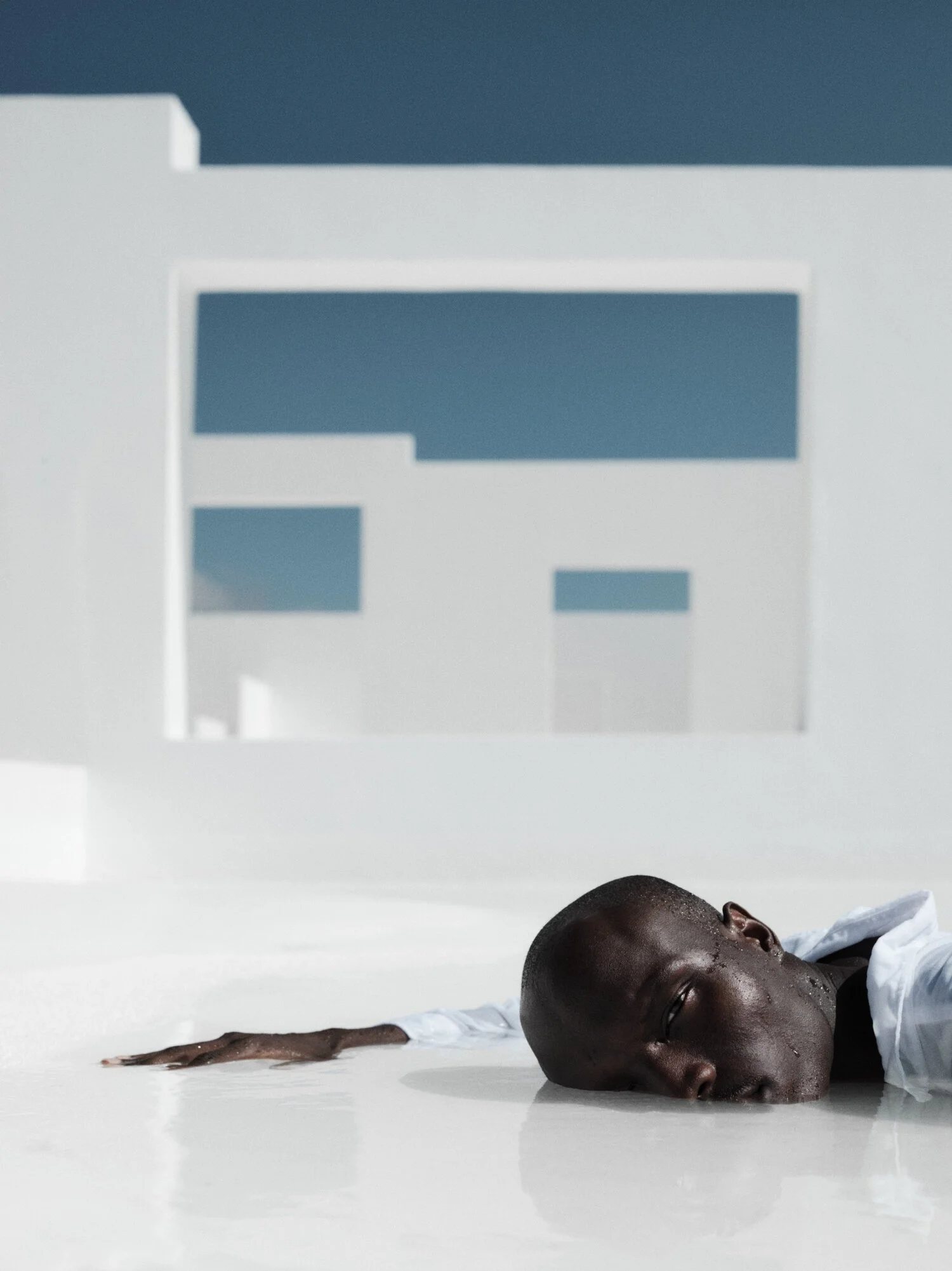 ANJEBA LYING ON A WHITE POOL EDGE WITH HIS FACE TOWARDS THE CAMERA, SHOWN UPSIDE DOWN.