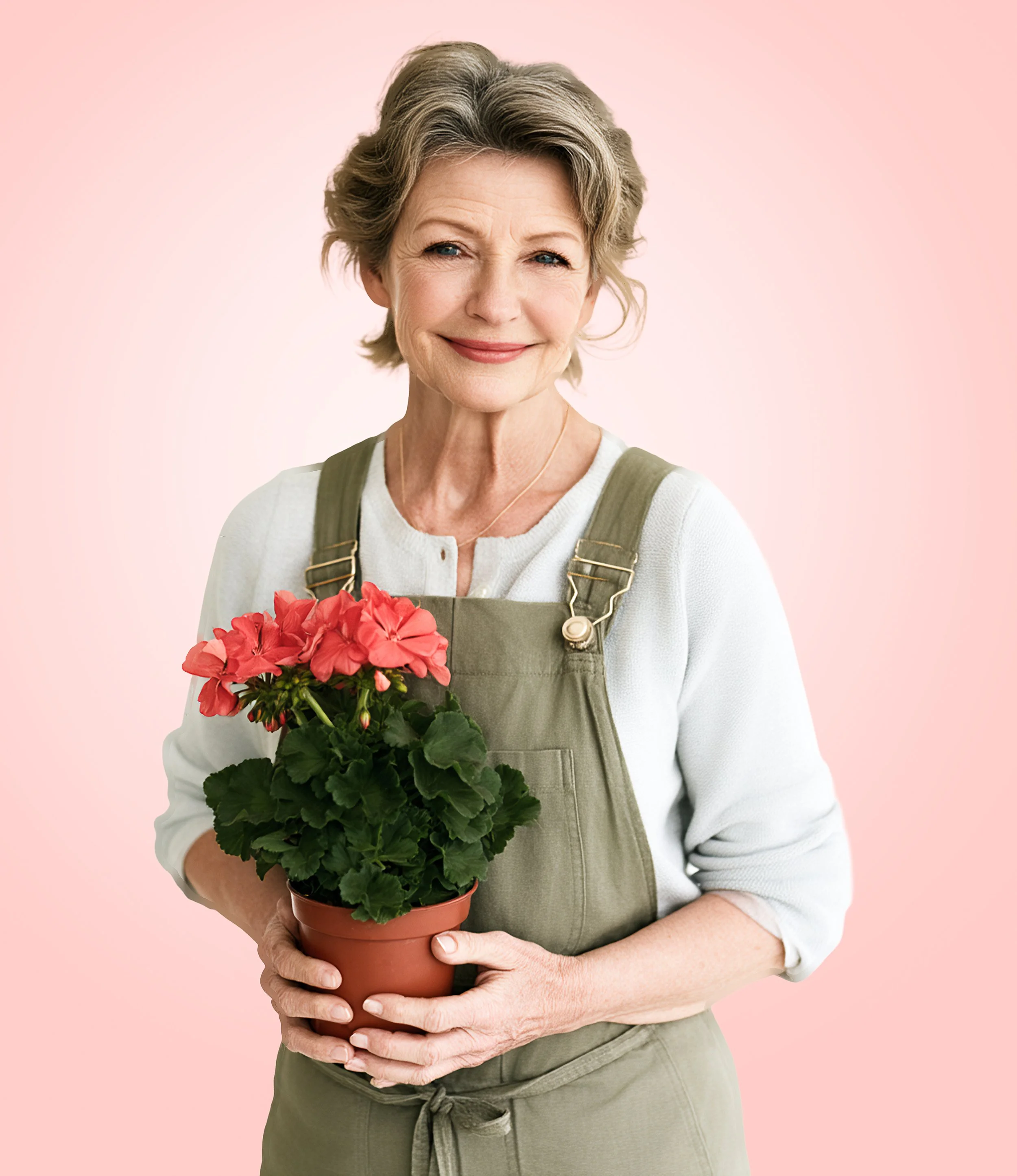 Woman in olive-green overalls holding a potted red geranium against a pale pink studio background.