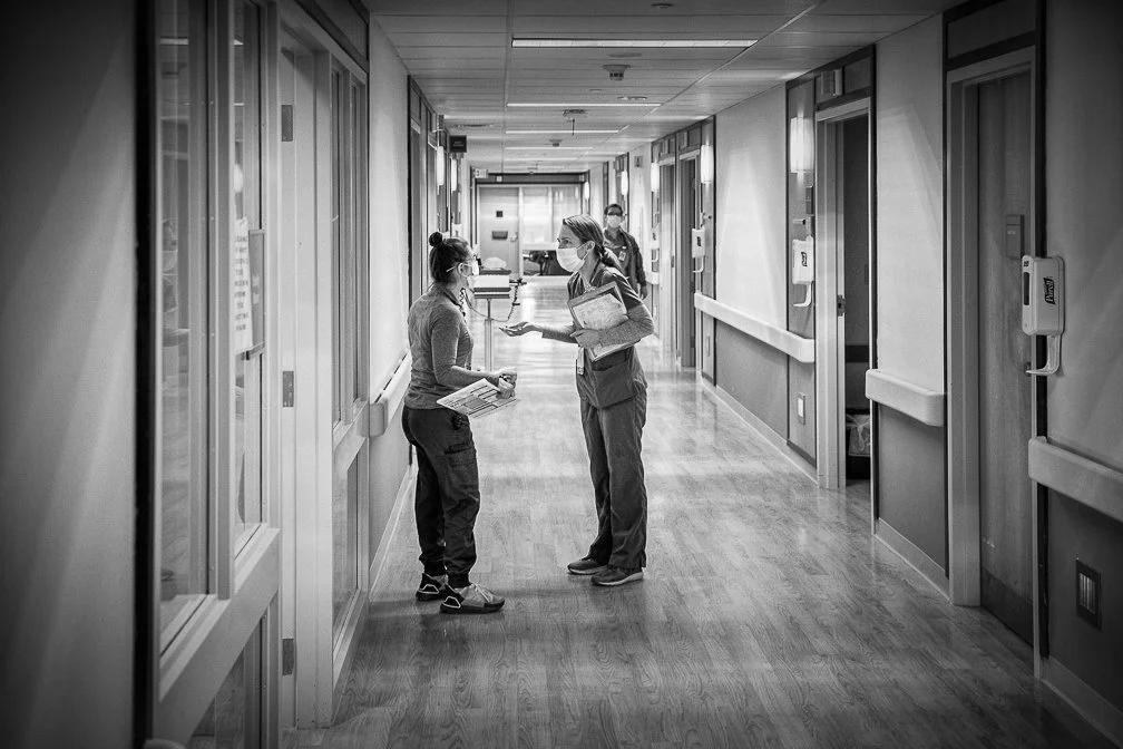 Two nurses engaged in a heated discussion in the ICU hallway, capturing the intensity of the Covid crisis.