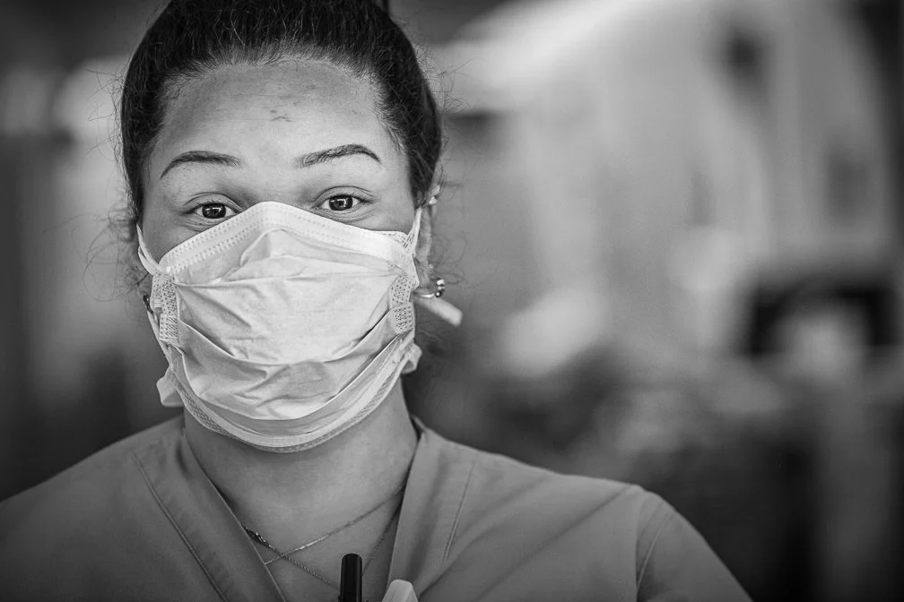 An extreme close-up portrait of an ICU nurse wearing a face mask, capturing the intensity of her gaze.