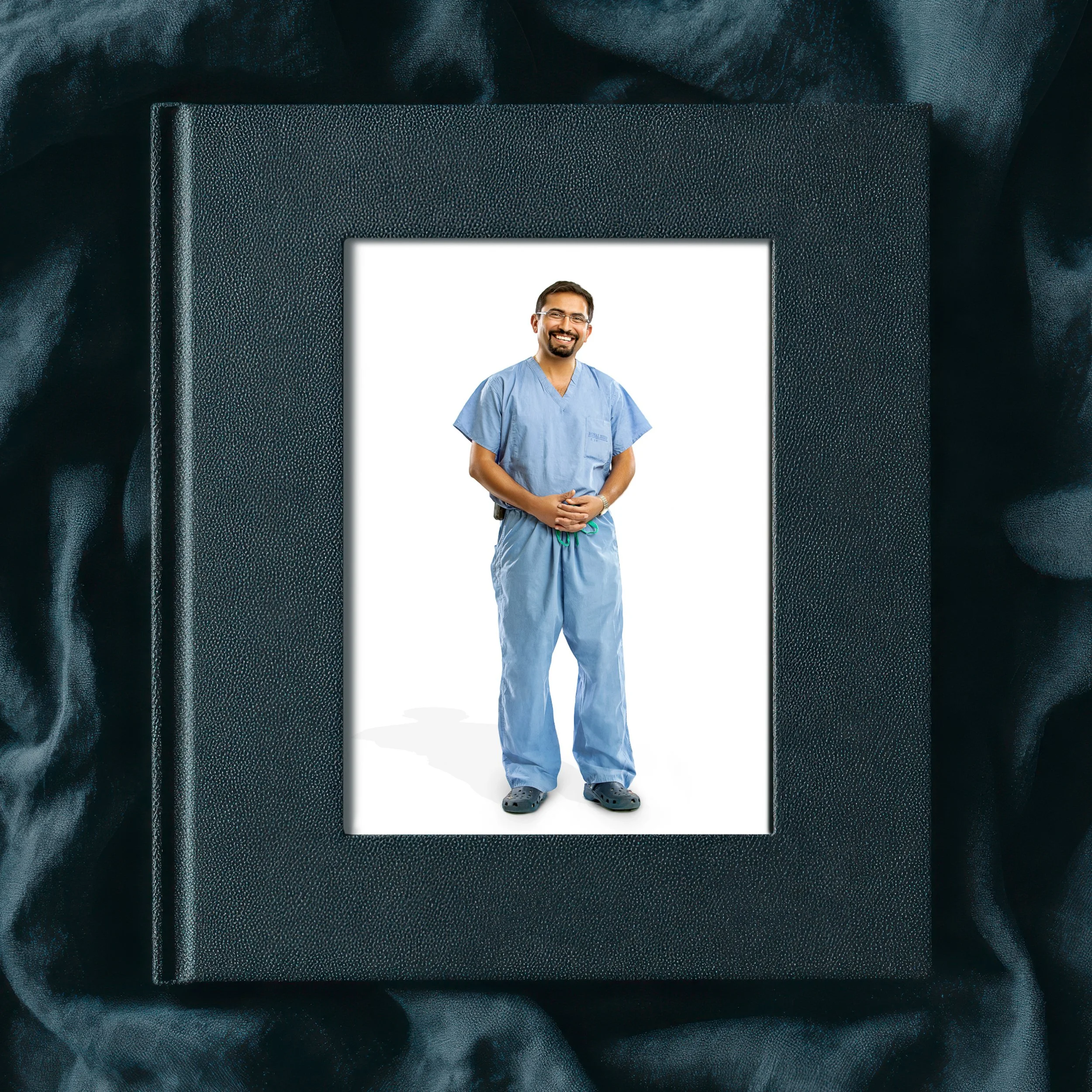 Photo album resting on dark fabric, with a cover portrait of a smiling man standing in blue medical scrubs.