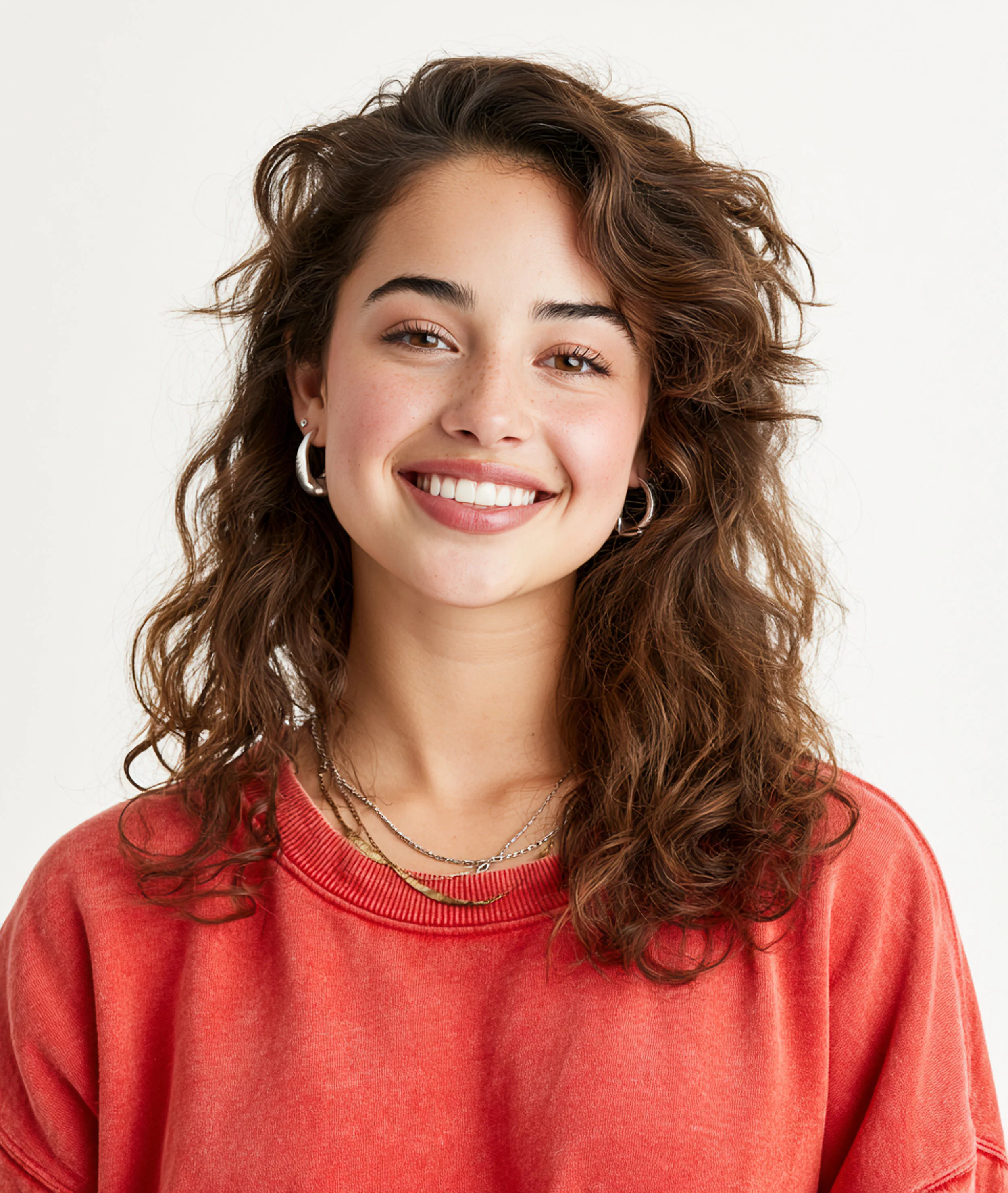 A close-up studio portrait of a smiling young woman with long brown hair wearing a red sweater.