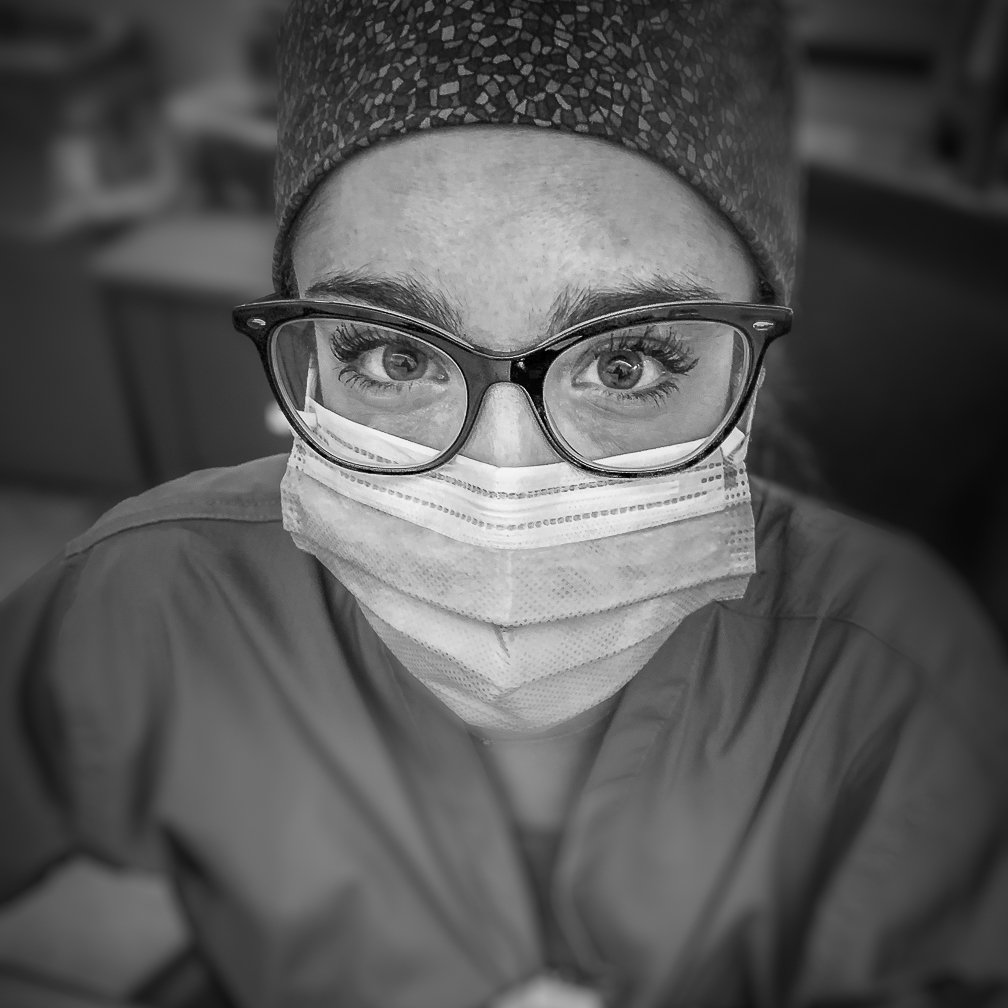 A female doctor looks up at the camera with a determined gaze, reflecting her unwavering commitment to patient care.