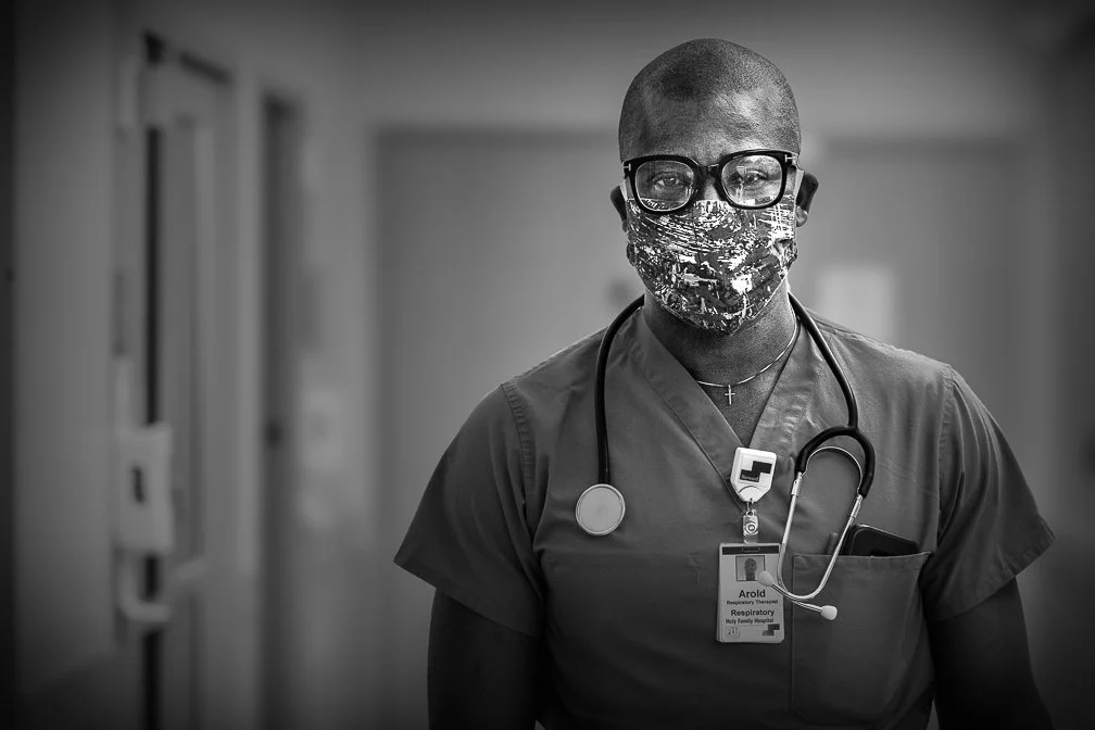 A young doctor stands heroically with a face mask and stethoscope, embodying the resilience and bravery of healthcare workers.