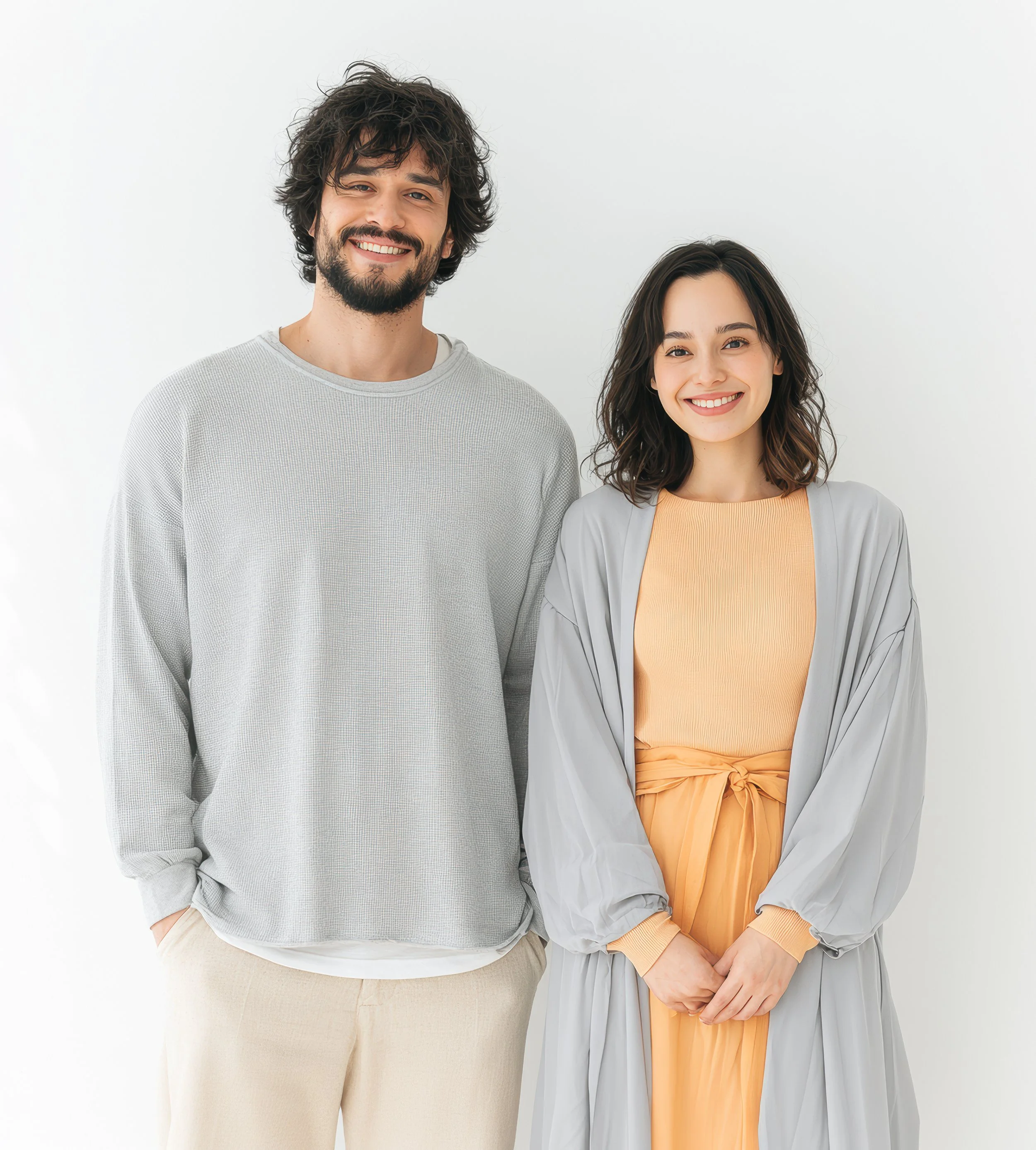A smiling young man and woman standing together against a clean white studio background.
