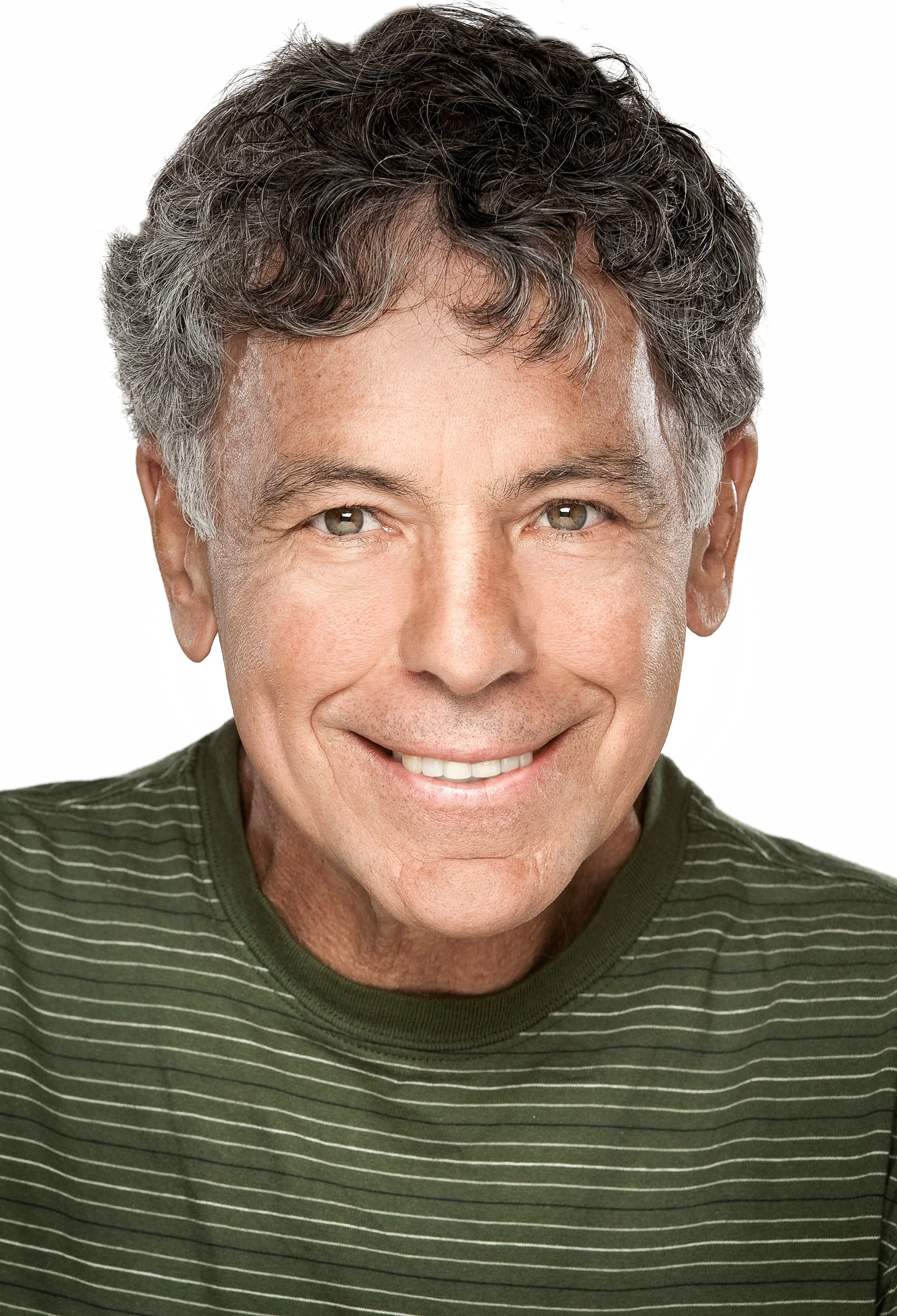 A close-up studio portrait of a smiling older man wearing a green striped shirt.