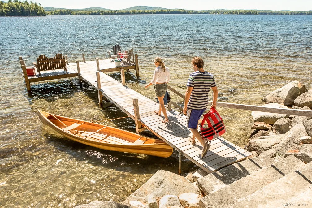 A family walking out to join friends for a lakeside dinner at dusk at Lake Winnipesaukee.