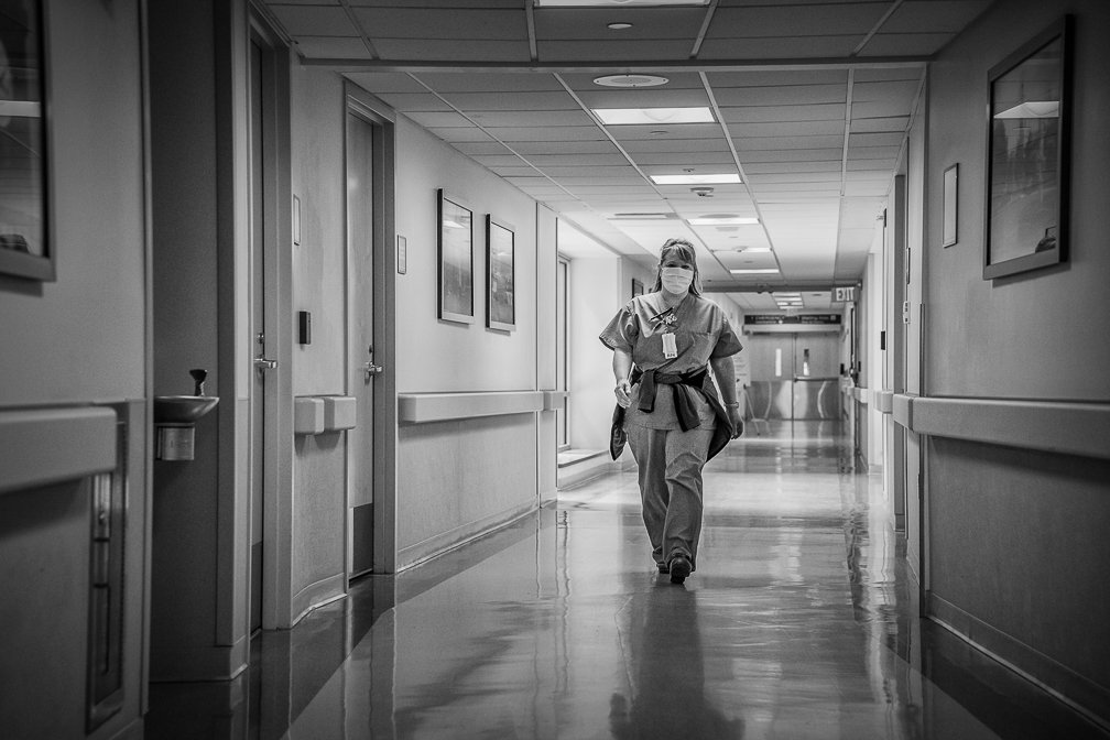 A lone female nurse hurrying along an empty corridor on a Covid patient floor, capturing the urgency and solitude.