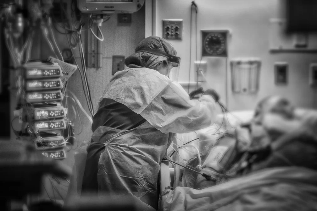 An ICU nurse carefully checking life support systems to a Covid patient, highlighting the urgency and care in the ICU.
