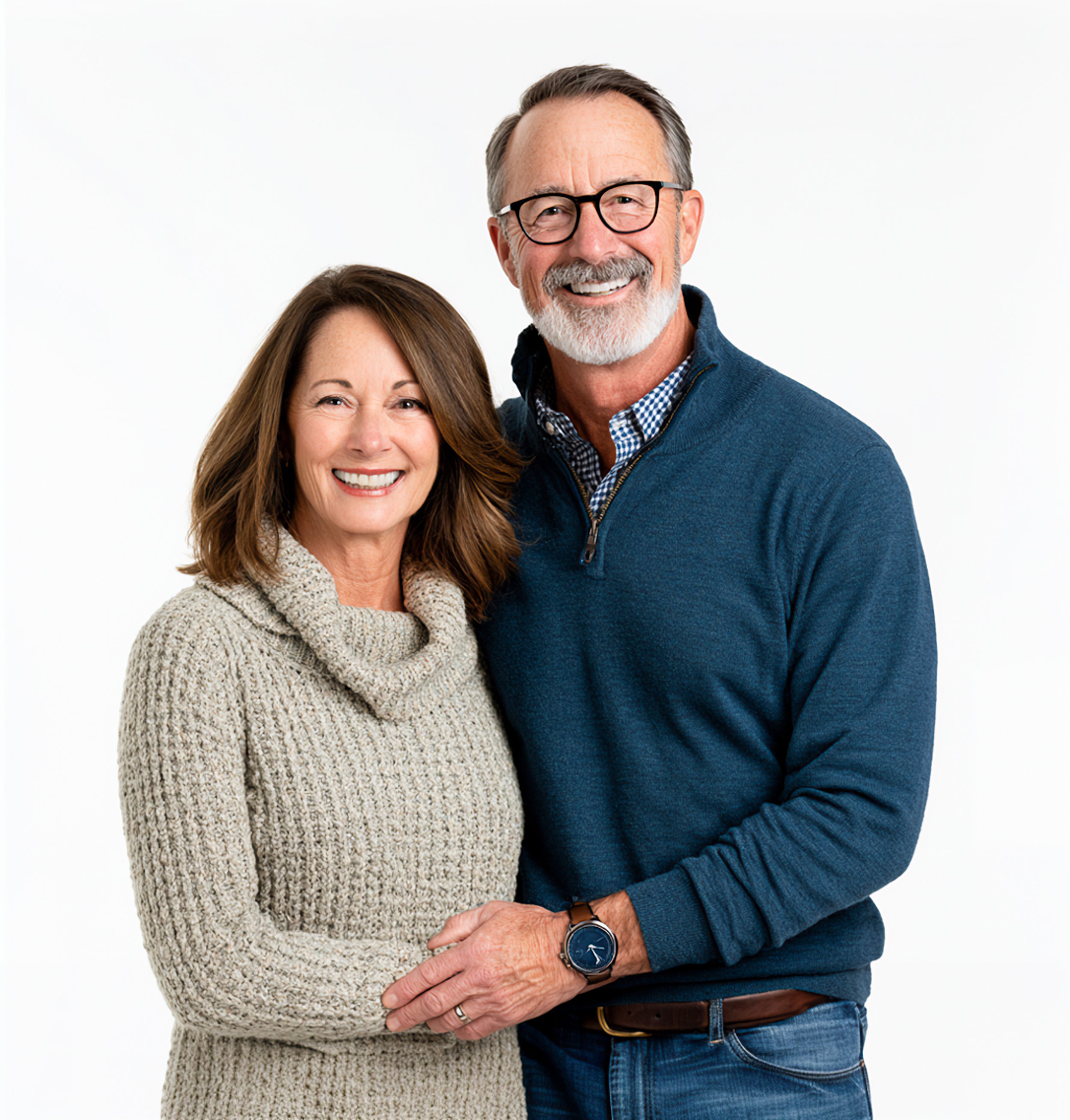 A relaxed portrait of a smiling mature couple standing together against a softly lit white background.
