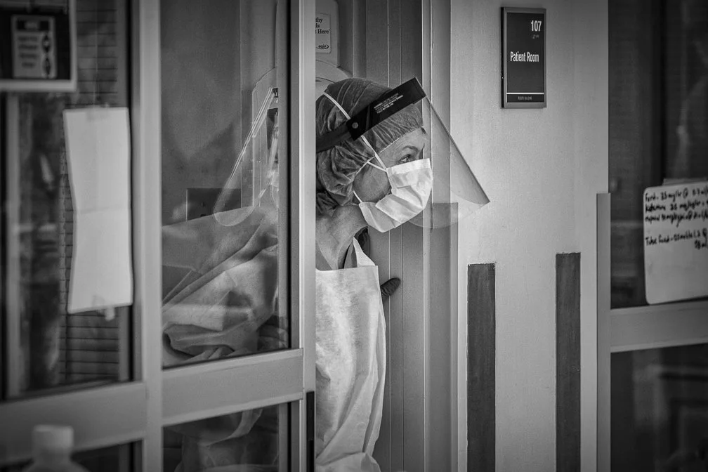 A female ICU doctor emerges from a Covid patient Intensive Care room, wearing full safety gear.