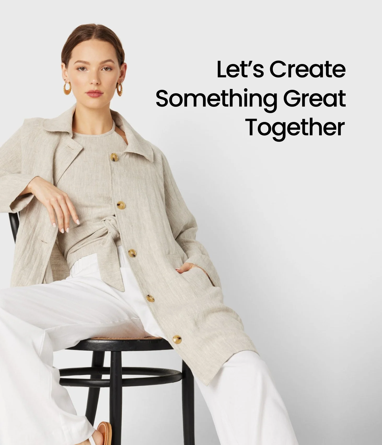 A woman in neutral-colored clothing sitting on a black stool with a message that reads "Let's Create Something Great Together" positioned to her right.