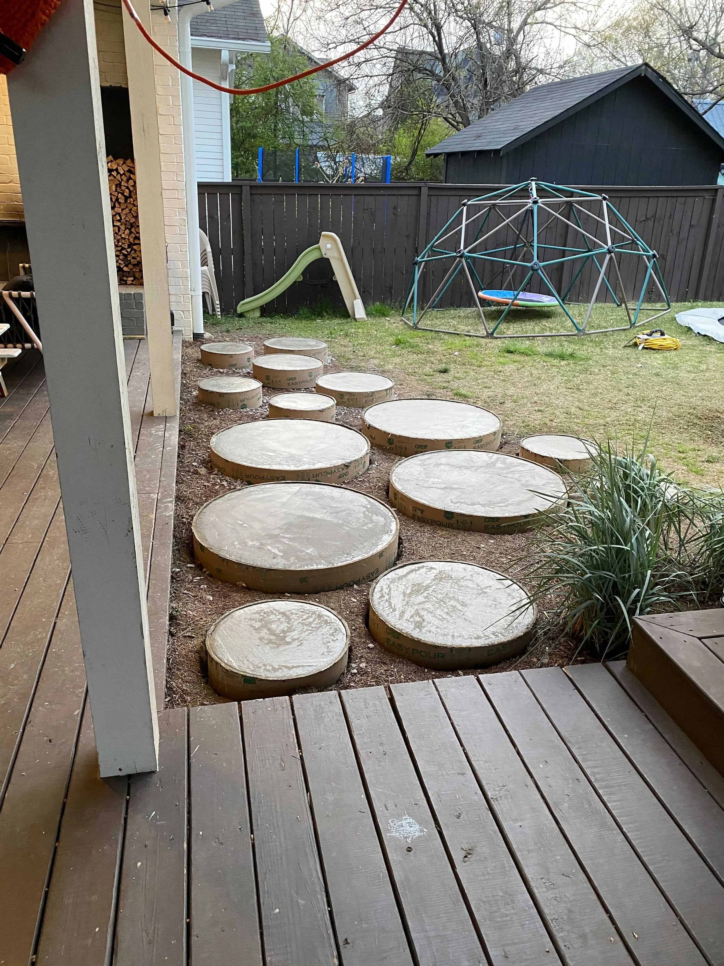 Backyard with stepping stones, a slide, and a climbing dome.