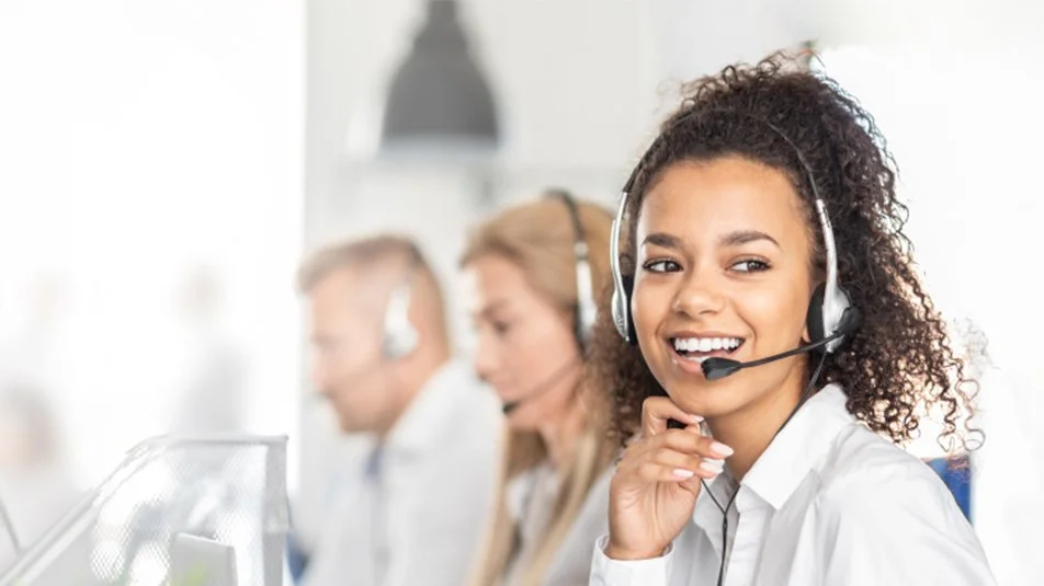 Customer service agents with headsets working at computers in an office.