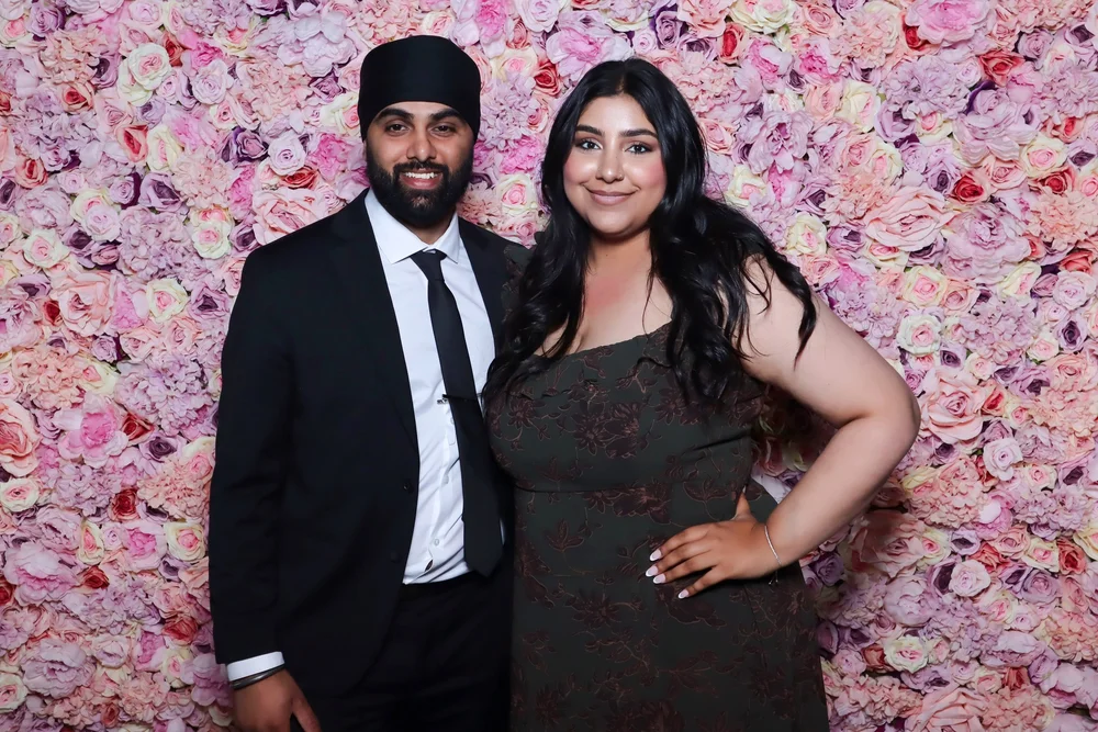 A couple in front of the pink flower wall