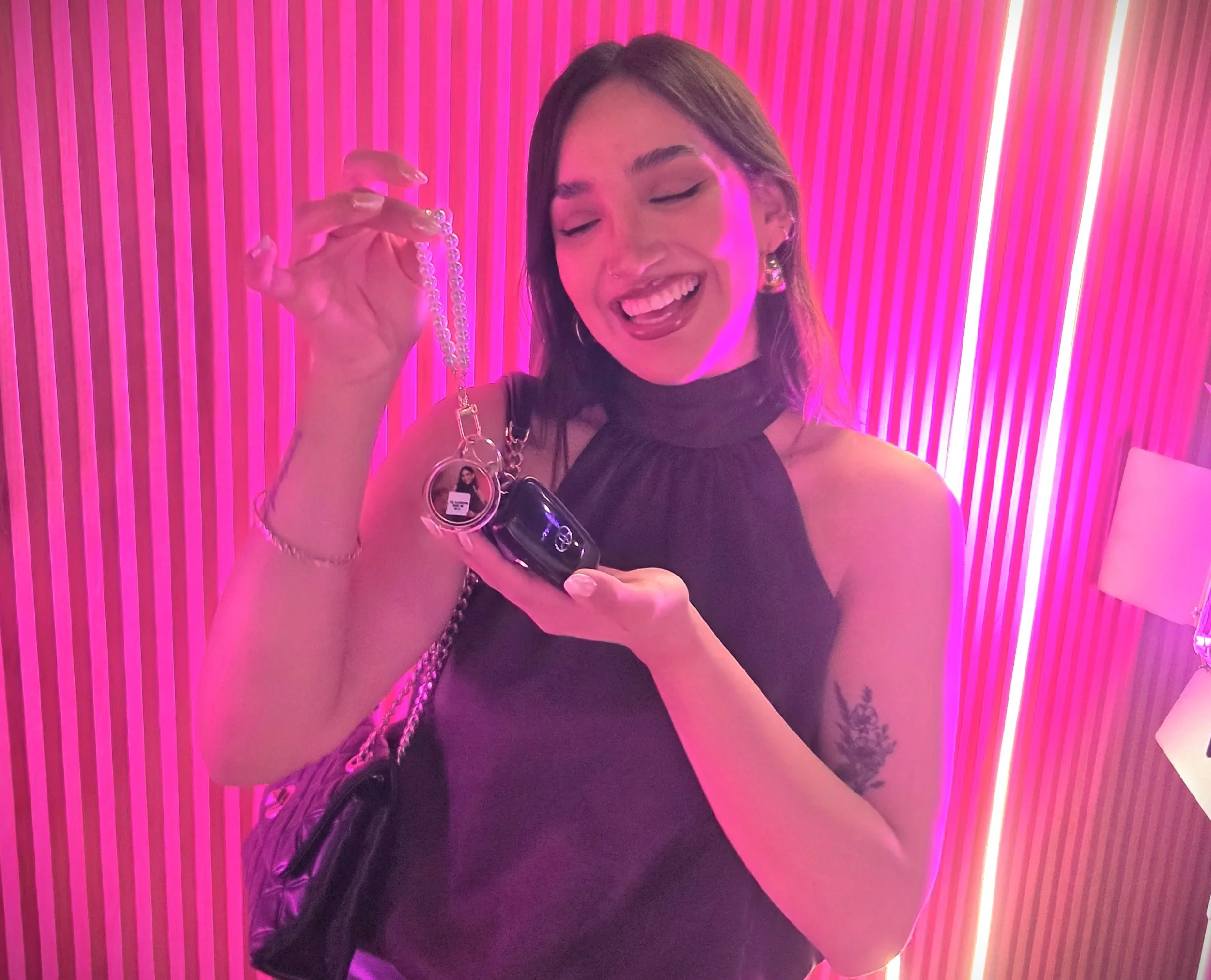 a woman holding a pearl keychain with a photo attached to her keys
