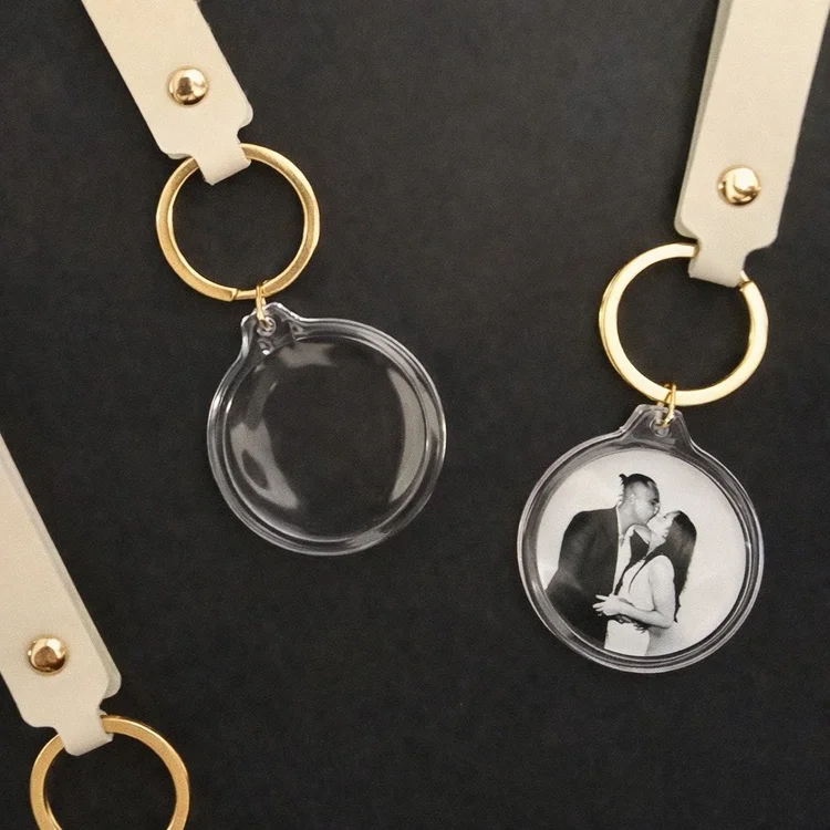 Acrylic photo keychains on cream leather straps, one holding a photo of a couple kissing