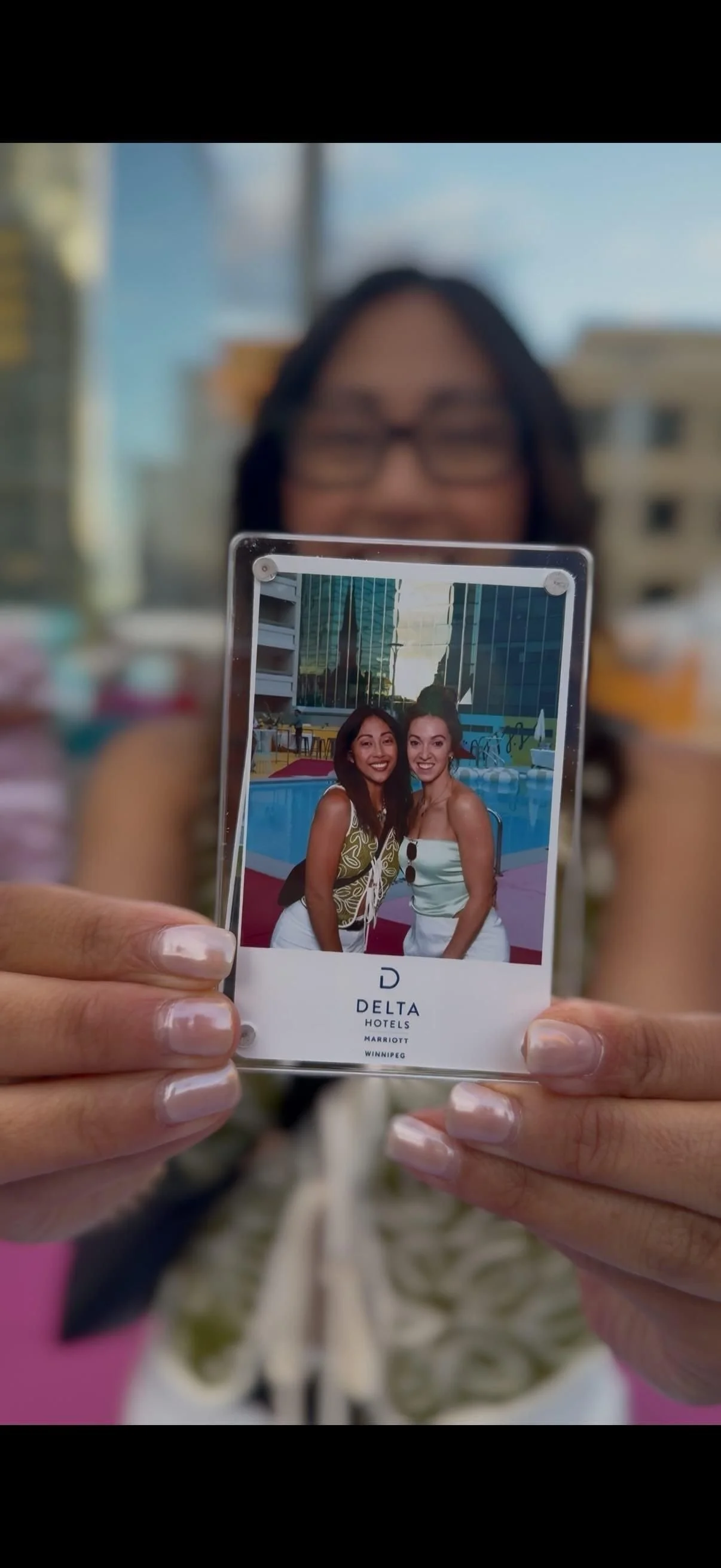 A guest holding up her acrylic photo magnet with the Delta Hotels Winnipeg logo at a rooftop event