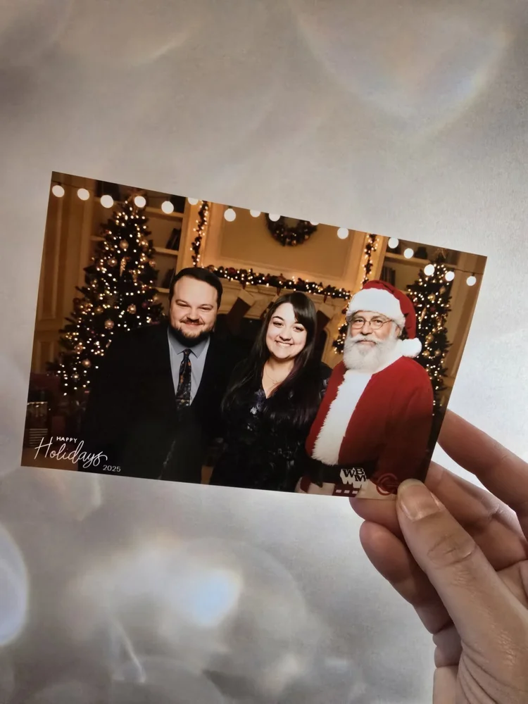 A guest holding a holiday print with Santa by the fireplace from the AI photo booth