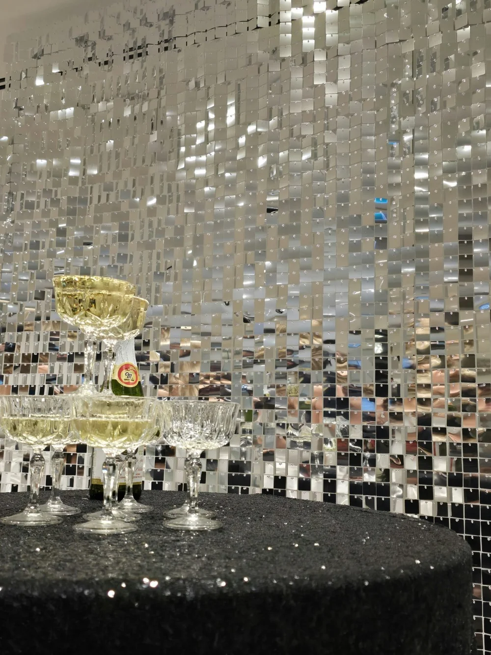 A champagne tower in front of the Silver Shimmer sequin wall