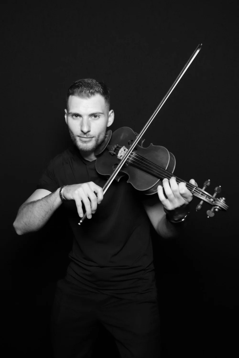 A violinist in a black and white glam portrait on a black backdrop