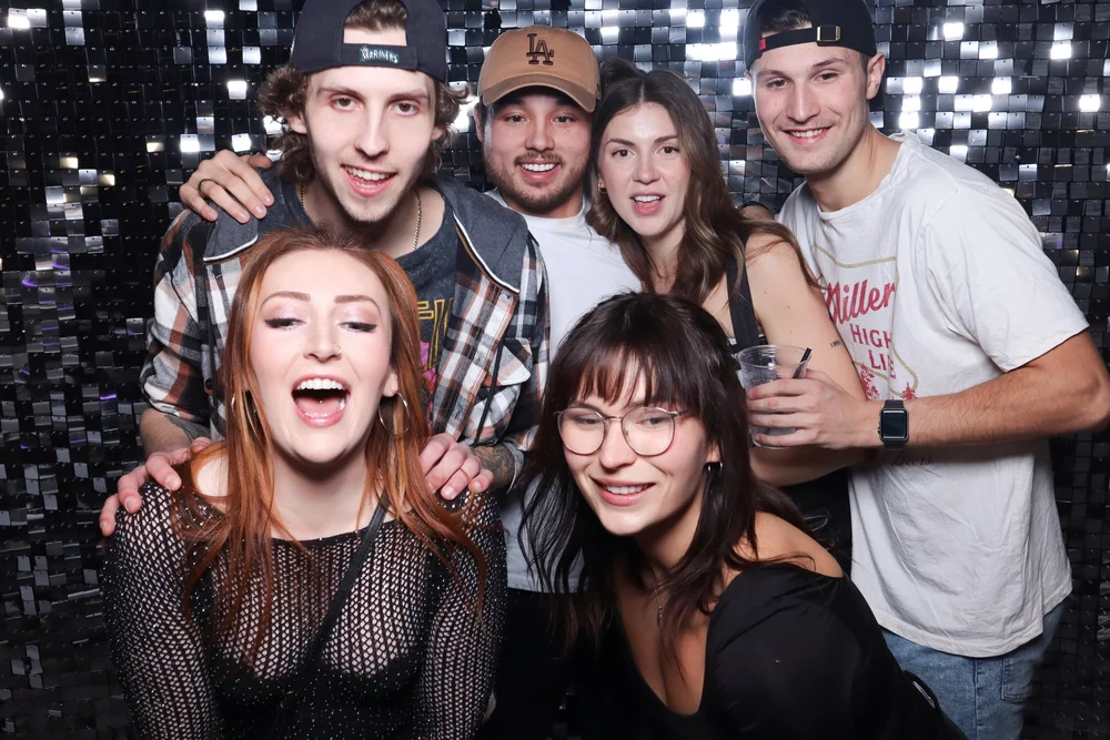 A group of friends in front of the Silver Shimmer wall on New Year's Eve