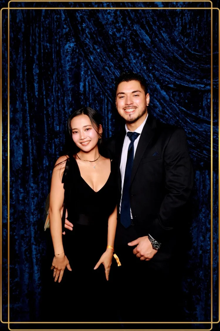 Couple in formal wear in front of blue crushed velvet draping at a Winnipeg holiday gala