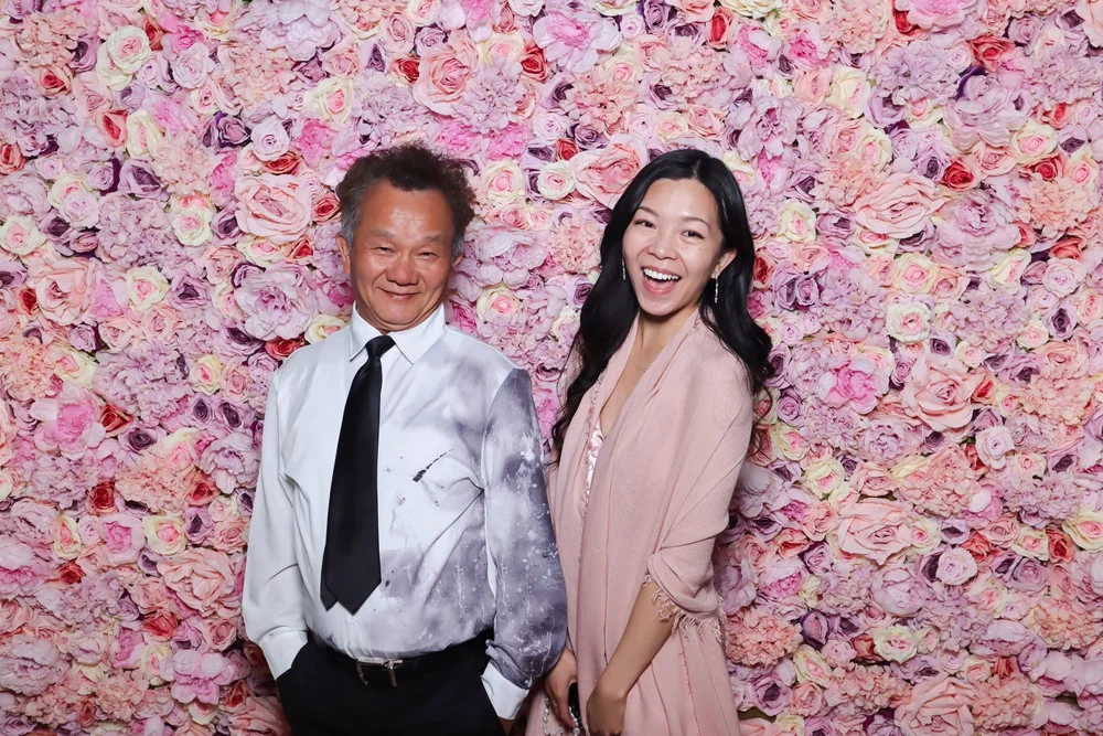 A couple in front of the Pastel Dreams pink flower wall