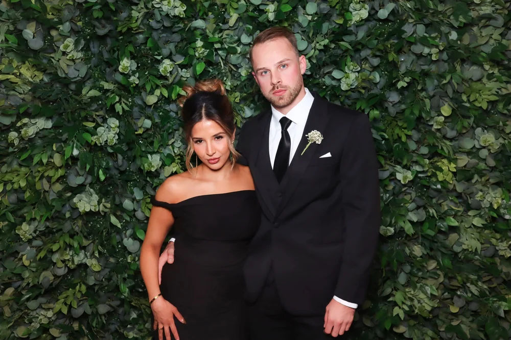 A couple in front of the green foliage wall