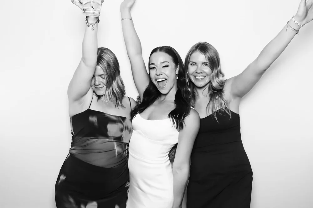 Three friends celebrating in a black and white glam portrait from On Que Photo Booth