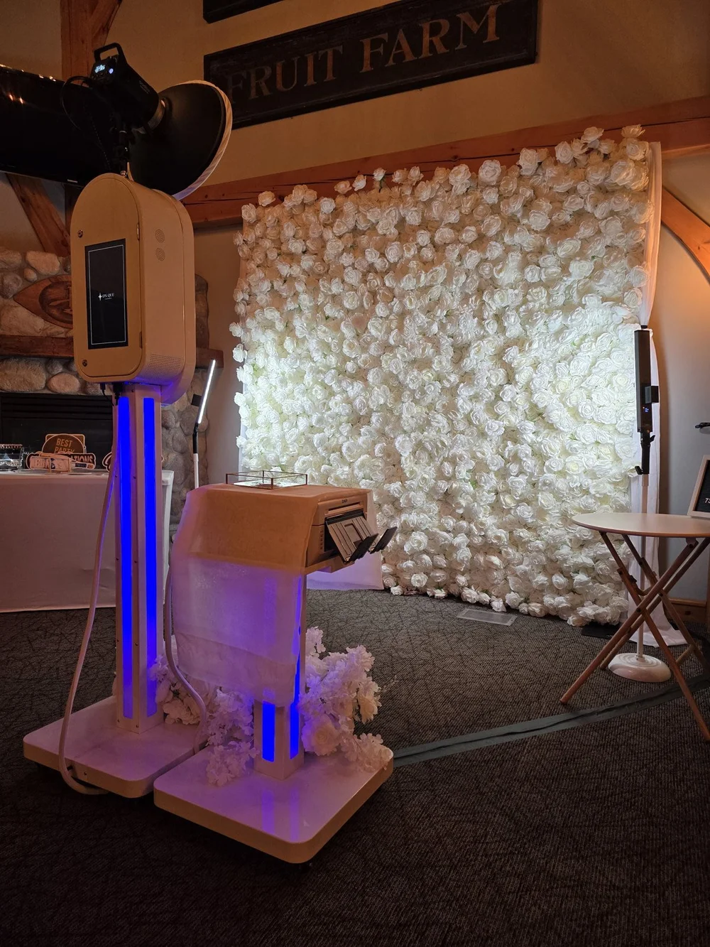 The Aura booth, column lit blue, in front of a white rose flower wall at Bridges Golf Course in Winnipeg