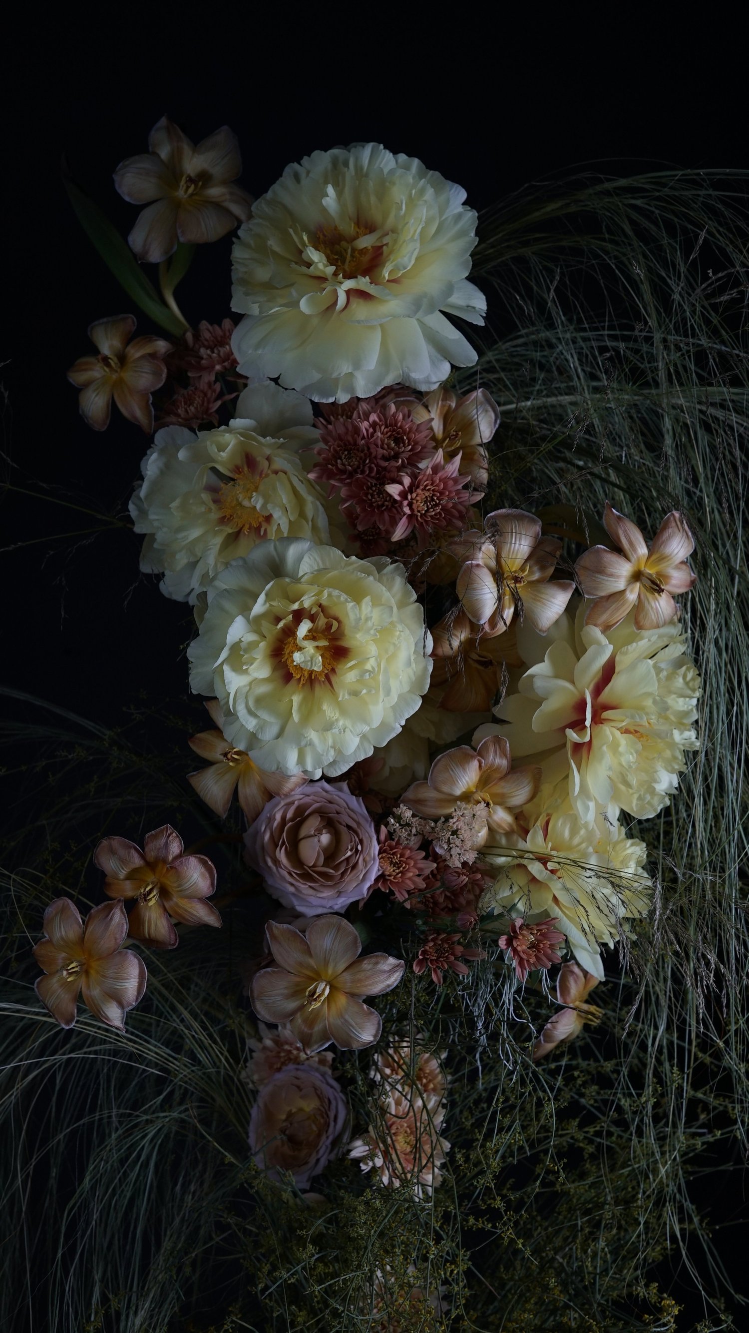 Arreglo floral en tonos crema y rosado sobre fondo oscuro