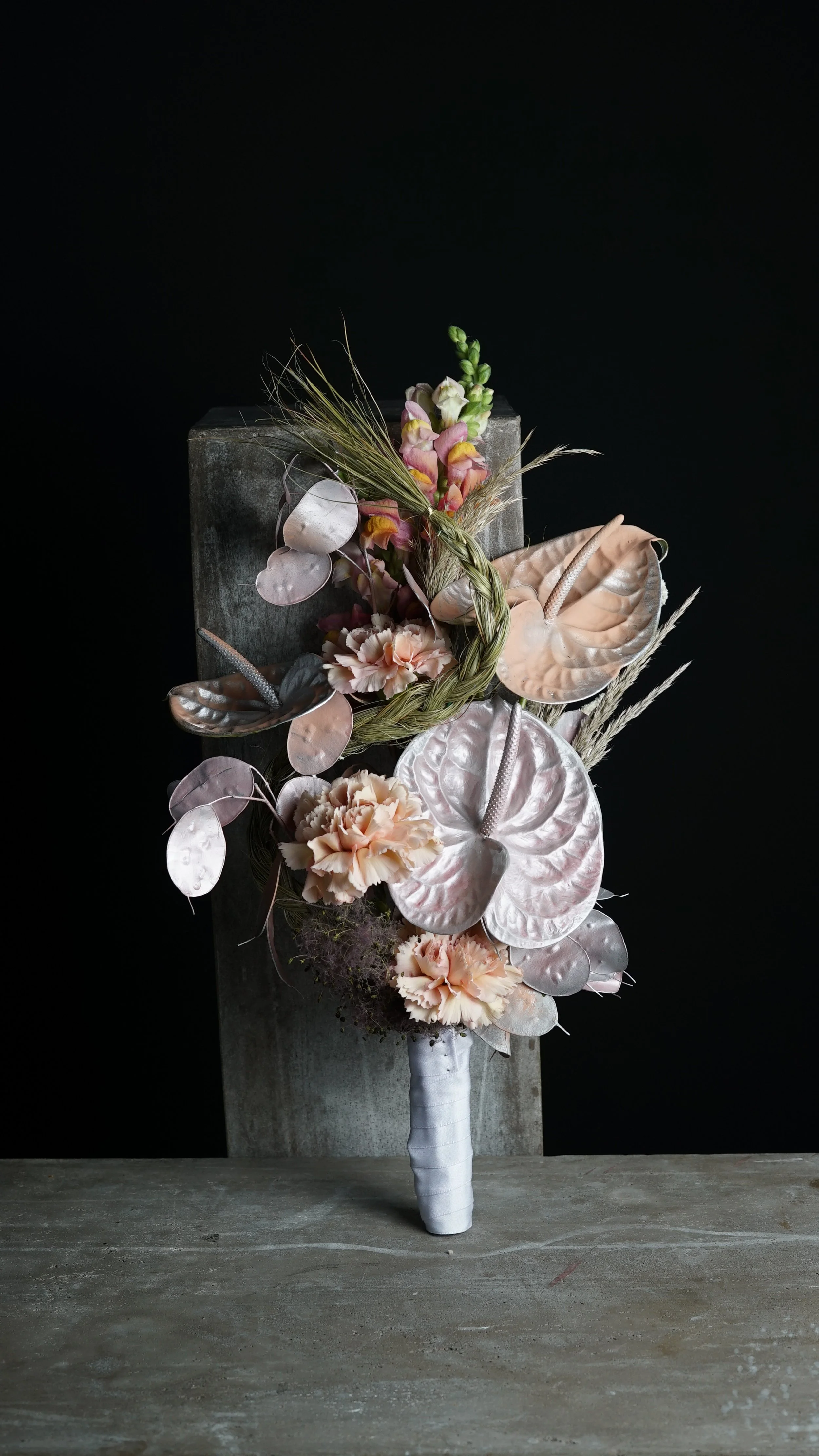 Ramo de flores con flores de color rosa y marfil sobre fondo oscuro.