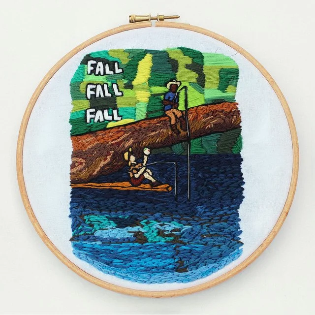 Embroidery of two people fishing near a lake, with a wooded hillside in the background and the word 'FALL' repeated three times.
