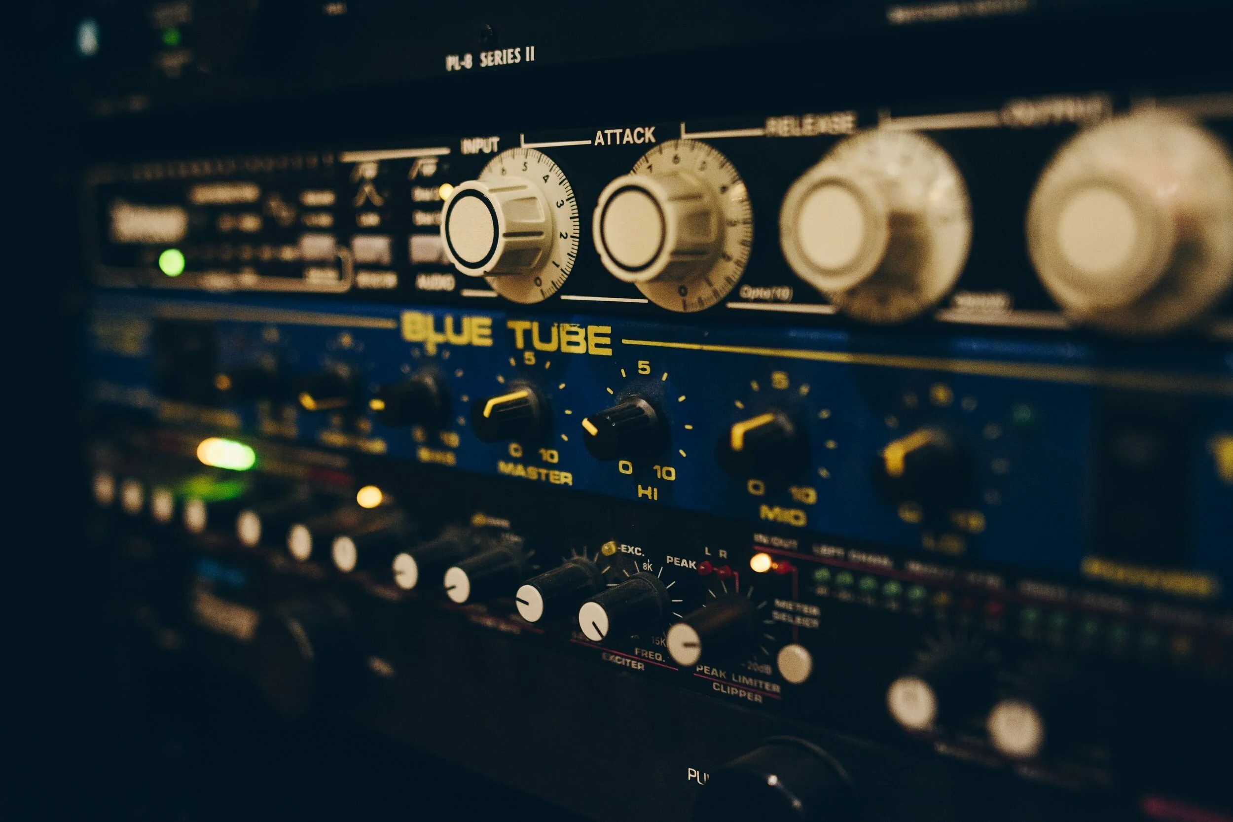 Audio mixing equipment, including blue tube graphic equalizer with various knobs and controls.